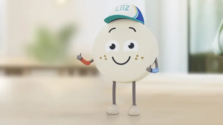 Maskottchenfigur mit Mütze Runde Figur mit Mütze steht auf Tisch.